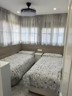 two beds in a small bedroom with curtains at LA BARROSA-NOVO SANCTI PETRI, wifi, aire acondicionado, parking in Chiclana de la Frontera