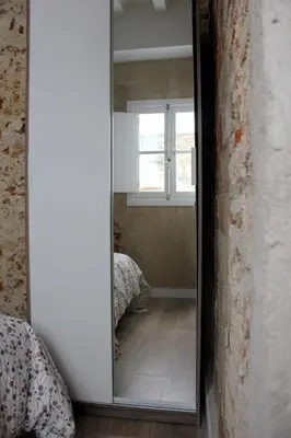 a mirror in a room with a bed and a window at Plaza de España building in Cádiz