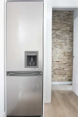 a stainless steel refrigerator in a room with a brick wall at Plaza de España building in Cádiz