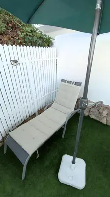 a white bench sitting on the grass under an umbrella at Apartamento La Barrosa - Chiclana - Urb. Pinar Atlántico in Chiclana de la Frontera