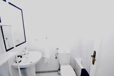 a white bathroom with a toilet and a sink at Apartamento La Barrosa - Chiclana - Urb. Pinar Atlántico in Chiclana de la Frontera