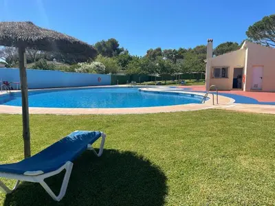 a man standing next to a swimming pool at Apartamento La Barrosa - Chiclana - Urb. Pinar Atlántico in Chiclana de la Frontera