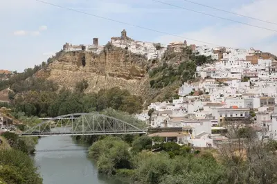 a bridge over a river in front of a mountain at Duque de Boliches in Arcos de la Frontera