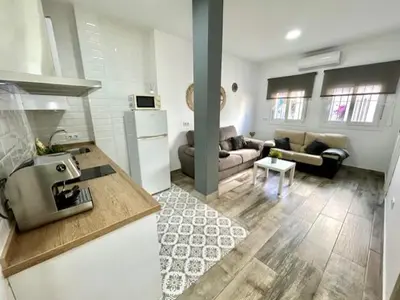 a kitchen and a living room with a couch at GATU La Murallita en Puerto Sherry in El Puerto de Santa María