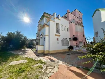 a large white and pink house with the sun in the sky at GATU La Murallita en Puerto Sherry in El Puerto de Santa María