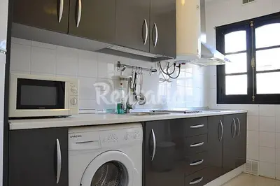 a kitchen with a washing machine and a microwave at Ático Cadiz al lado playa la Caleta in Cádiz