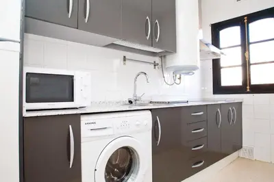 a kitchen with a washing machine and a microwave at Ático Cadiz al lado playa la Caleta in Cádiz