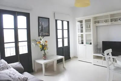 a living room with a couch and a table with flowers at Ático Cadiz al lado playa la Caleta in Cádiz