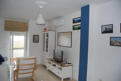 a living room with a tv and a desk with a computer at Torre de la Galeona in El Puerto de Santa María