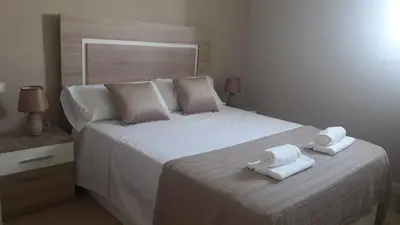 a bedroom with a large white bed with towels on it at ATICO BAHÍA in Cádiz