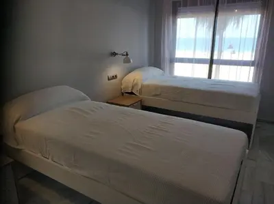 two beds in a room with a window at Victoria Beach Sunset Lounge in Cádiz