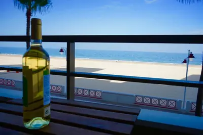 a bottle of wine sitting on a balcony overlooking the beach at Victoria Beach Sunset Lounge in Cádiz
