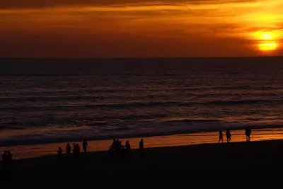 a group of people standing on the beach at sunset at Victoria Beach Sunset Lounge in Cádiz