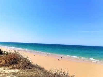 a beach with people walking on the sand and the ocean at Calma holiday home in Conil de la Frontera