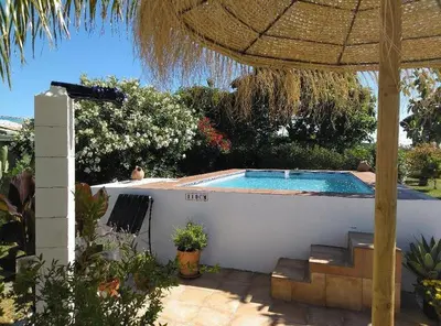 a backyard with a swimming pool and a umbrella at Villa de Limones in Chiclana de la Frontera
