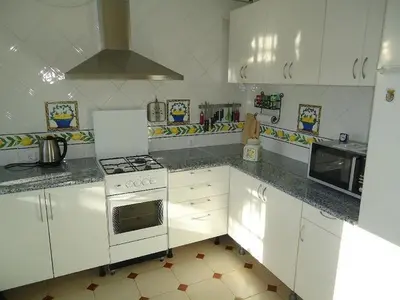 a kitchen with white cabinets and a stove top oven at Villa de Limones in Chiclana de la Frontera
