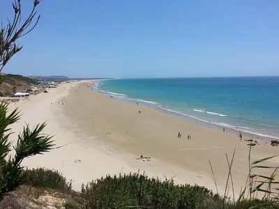a group of people on a beach near the ocean at Villa de Limones in Chiclana de la Frontera