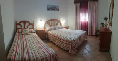 a hotel room with two beds and a window at La Orquídea Morada in Conil de la Frontera
