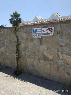a stone wall with two signs on it at La Orquídea Morada in Conil de la Frontera
