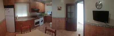 a kitchen with wooden cabinets and a tv in it at La Orquídea Morada in Conil de la Frontera