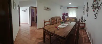 a living room with a wooden table and chairs at La Orquídea Morada in Conil de la Frontera