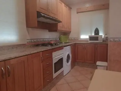 a kitchen with wooden cabinets and a white stove top oven at La Orquídea Morada in Conil de la Frontera