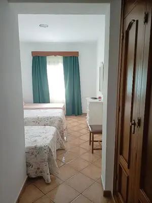 a bedroom with two beds and a table and a window at La Orquídea Morada in Conil de la Frontera