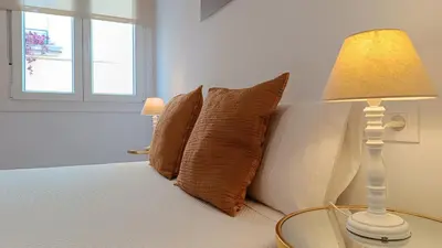 a bed with pillows and a table with a lamp at Sherryflat Torneria- Parking in Jerez de la Frontera