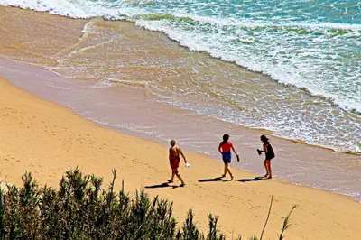 three people walking on a beach near the ocean at Apartamento con piscina comunitaria in Conil de la Frontera