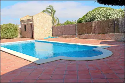a swimming pool in a yard with a brick patio at Apartamento con piscina comunitaria in Conil de la Frontera