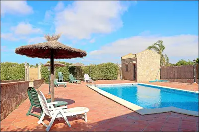 a swimming pool with an umbrella and chairs and a swimming pool at Apartamento en complejo con piscina in Conil de la Frontera