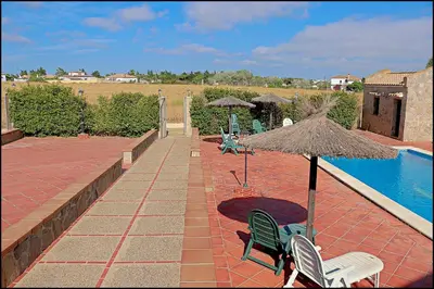 a patio with chairs and an umbrella next to a pool at Apartamento en complejo con piscina in Conil de la Frontera