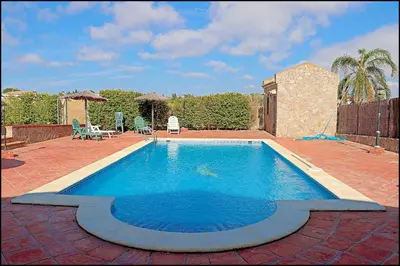 a large swimming pool on a brick patio at Apartamento en complejo con piscina in Conil de la Frontera