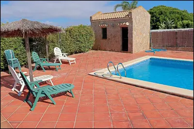 a patio with chairs and a swimming pool and an umbrella at Apartamento en complejo con piscina in Conil de la Frontera