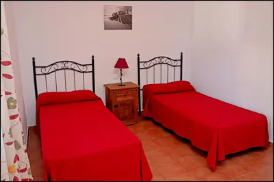 two beds in a room with red sheets at Apartamento Cala de Puntalejo in Conil de la Frontera