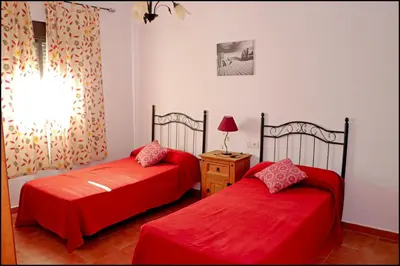 two beds in a room with red sheets at Apartamento Cala de Puntalejo in Conil de la Frontera