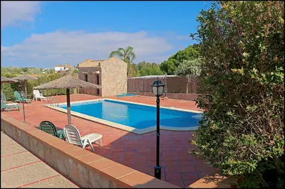 a swimming pool with two chairs and a light pole at Apartamento Cala de Puntalejo in Conil de la Frontera