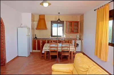 a kitchen with a table and a yellow couch in a room at Apartamento Cala de Puntalejo in Conil de la Frontera