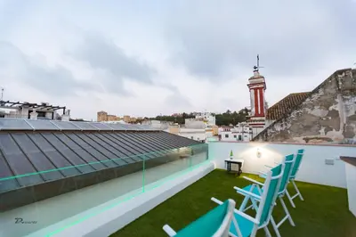 a balcony with chairs and a clock tower in the background at Fumiko in Sanlúcar de Barrameda