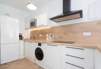 a kitchen with white cabinets and a washer and dryer at Fumiko in Sanlúcar de Barrameda