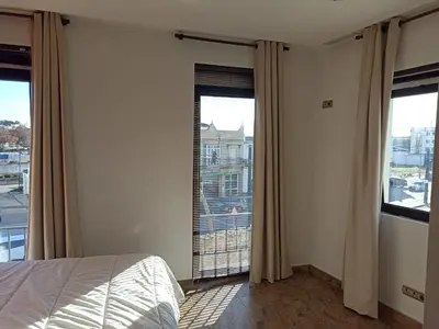 a bedroom with a bed and two large windows at Avenida Reyes Católicos in Chiclana de la Frontera