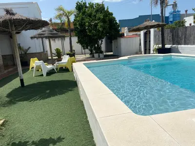 a swimming pool with an umbrella and tables and chairs at Casa con Piscina en Sanlucar de Barrameda in Sanlúcar de Barrameda
