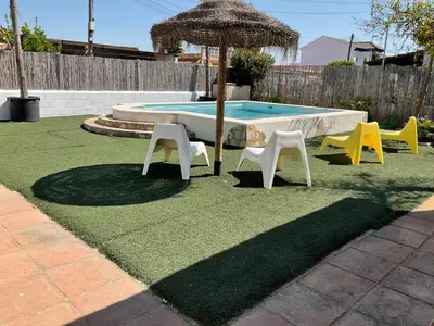 a pool with chairs and an umbrella and a table and chairs at Casa con Piscina en Sanlucar de Barrameda in Sanlúcar de Barrameda