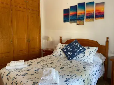 a bedroom with a bed and two paintings on the wall at Casa con Piscina en Sanlucar de Barrameda in Sanlúcar de Barrameda