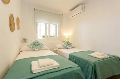 two beds in a white room with green sheets at Casa Ros-PLAYA free parking by Cadiz4Rentals in Cádiz