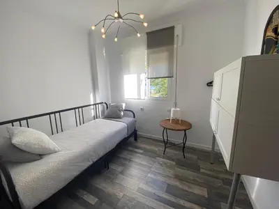 a bedroom with a bed and a table and a window at Casa Ana in Sanlúcar de Barrameda