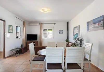 a dining room with a table and white chairs at Villa Ébano in Conil de la Frontera