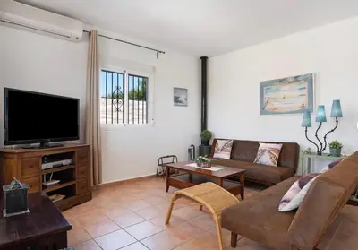 a living room with a couch and a tv at Villa Ébano in Conil de la Frontera