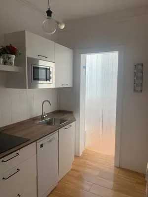 a kitchen with white cabinets and a sink and a window at Sanlúcar Playa in Sanlúcar de Barrameda