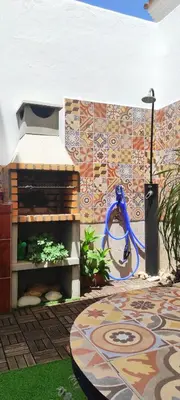 a patio with a tile wall with a blue hose at La Barrosa duplex in Chiclana de la Frontera